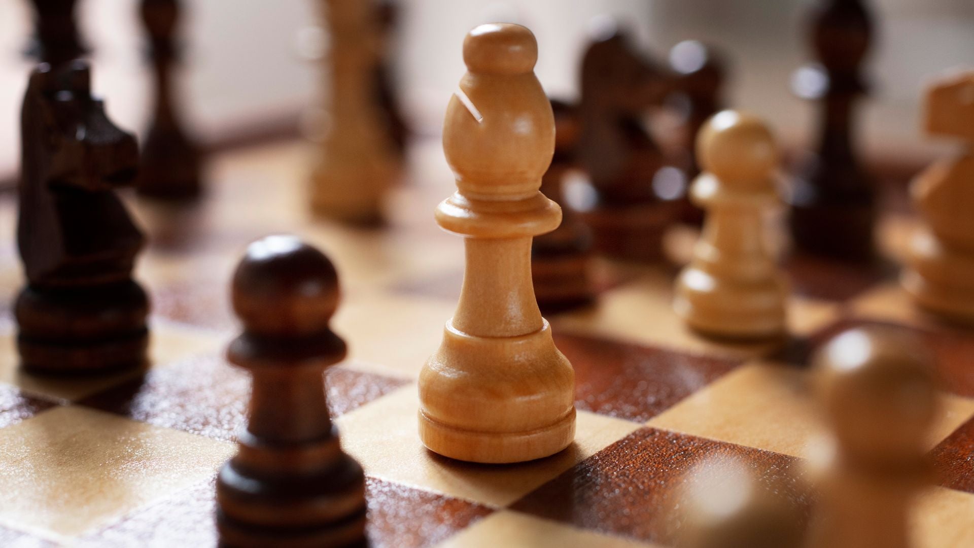 A close-up view of various chess pieces arranged on a classic chessboard, showcasing their intricate designs and colors.