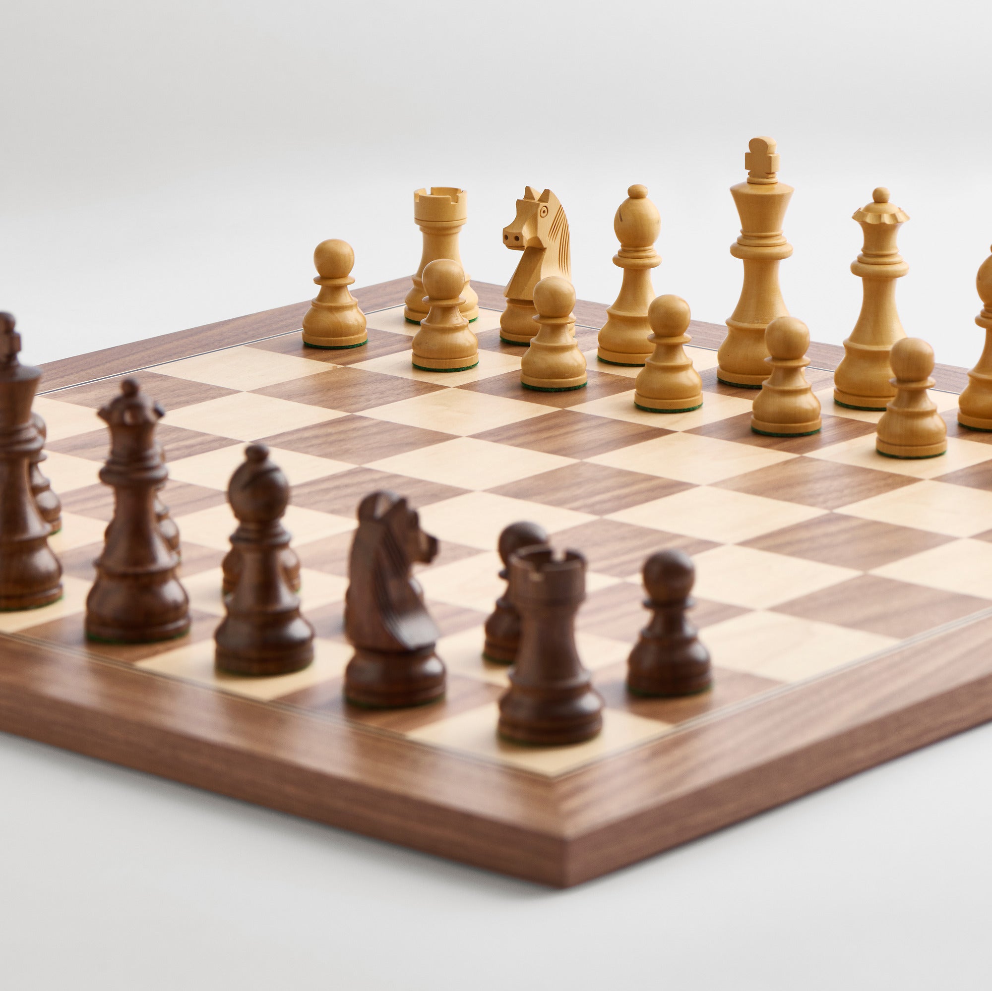 A wooden chess board displaying various chess pieces arranged for a game.